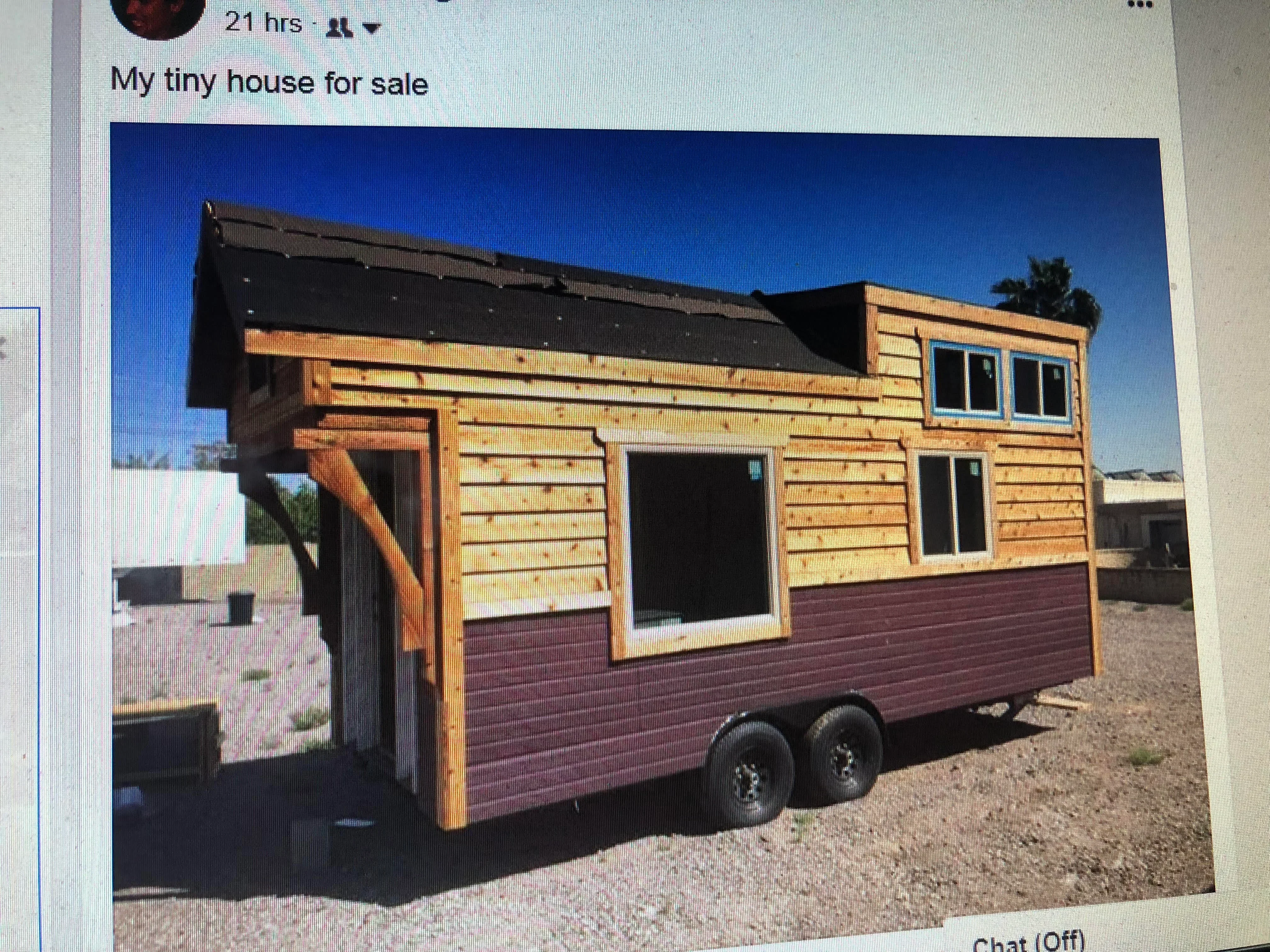 Tiny house on trailer with wood siding, metal roof, and multiple windows